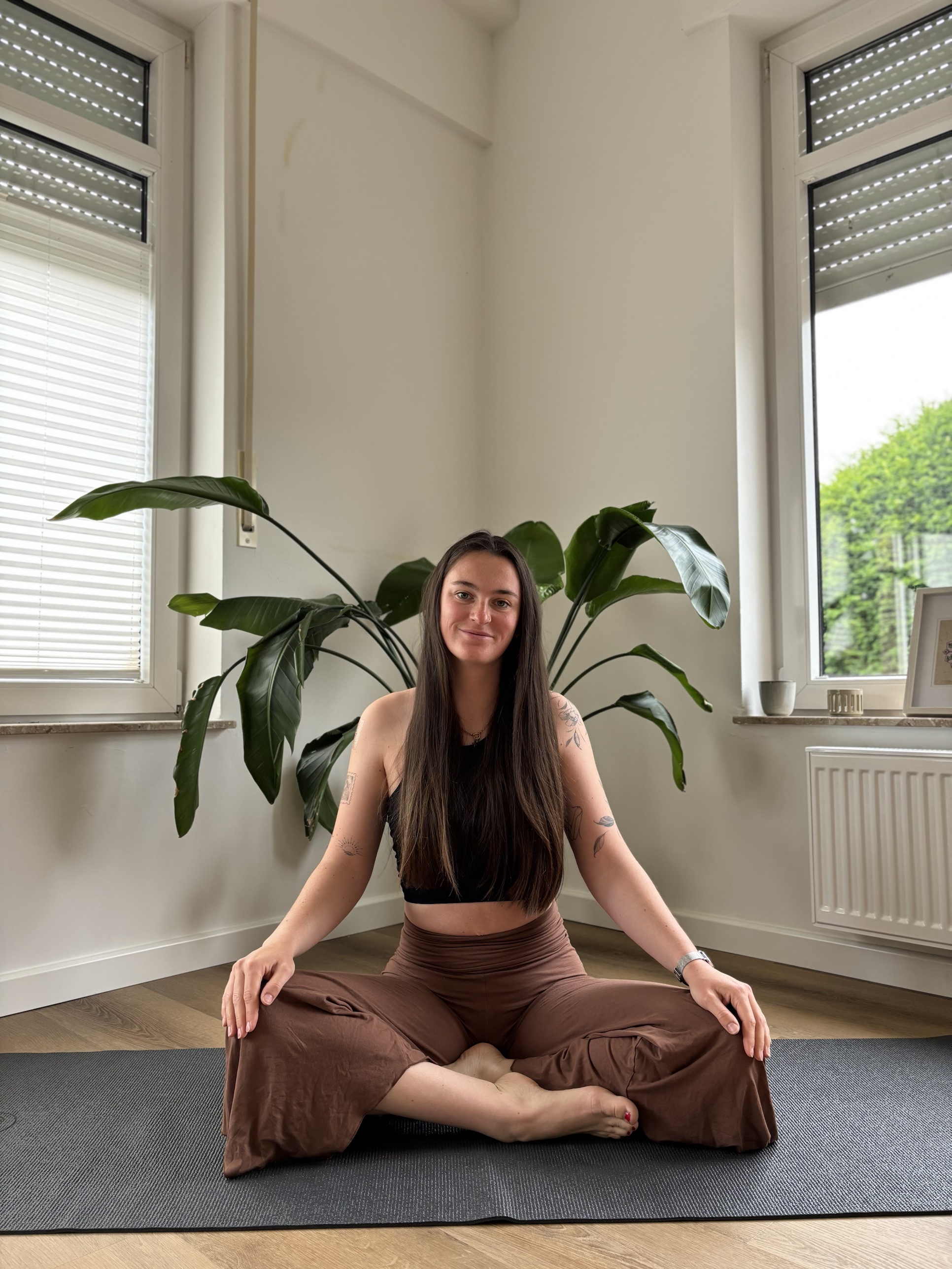 Hannah, sitzend im Schneidersitz auf einer Yogamatte